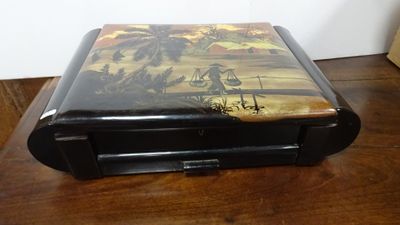 a black box with a painting on it on a wooden table
