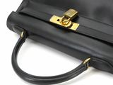 black leather handbag with a gold lock on a white background