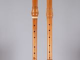 two wooden flutes on a clear surface with a grey background
