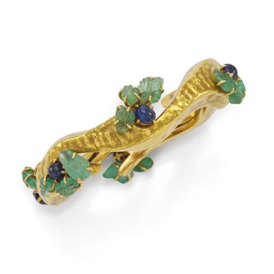 un gros plan sur une broche en or sertie de pierres vertes et bleues