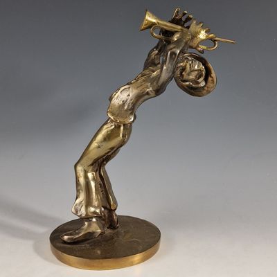 brass statue of a man playing a trumpet on a base