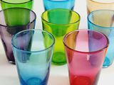 six different colored glasses sitting next to each other on a table