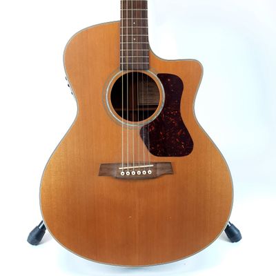an acoustic guitar sitting on a stand against a white background