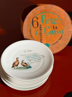 a stack of plates sitting on a table with a clock in the background