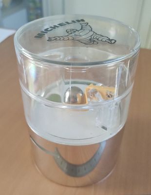 un verre d'eau posé sur une table, avec une cuillère dedans