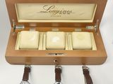 trois montres dans un coffret en bois, avec des bracelets en cuir, posées sur un fond blanc