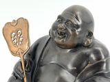 a statue of a laughing buddha holding a fan