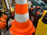 orange and white traffic cone sitting on top of a pile of tools