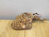 tan leopard print sandals on a wooden table with a white wall in the background