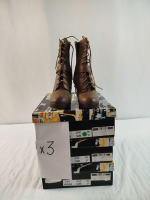 une paire de bottes marron posée sur une boîte, elle-même posée sur un lit