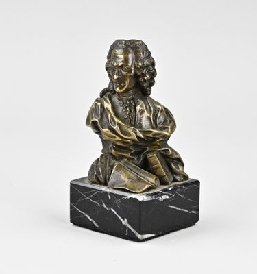 une statue en bronze représentant un homme assis sur un bloc de marbre
