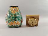 a small vase with a clock on it next to it