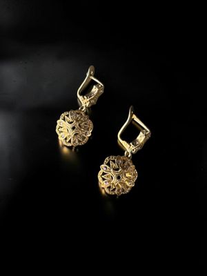 a pair of gold earrings on a black background