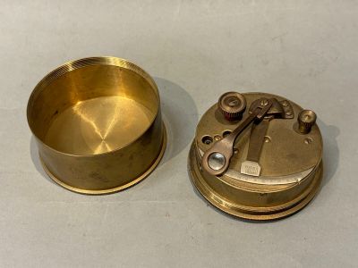 un petit objet en laiton posé sur une table, à côté d'un autre, plus petit