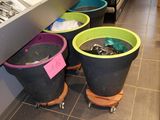 three buckets that are sitting on wheels in a kitchen