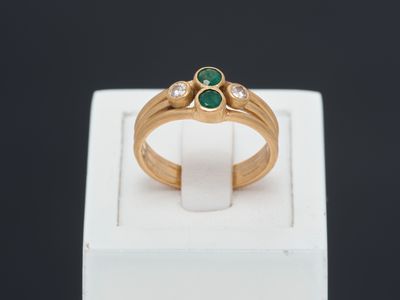 a close up of a gold ring with two emerald stones