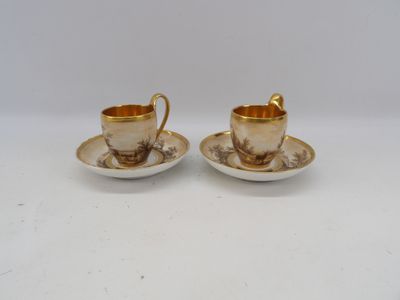 two cups and saucers are sitting on a white surface