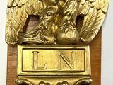 un aigle en or sur une plaque en bois avec une horloge