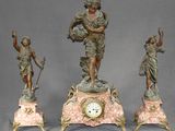 trois statues représentant une femme et un homme sur une horloge