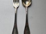 two silver spoons and a fork on a table