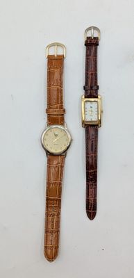 two watches are sitting next to each other on a white surface