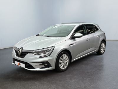Une voiture argentée est garée dans une pièce aux murs blancs.