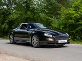 a black sports car driving down the road in the woods