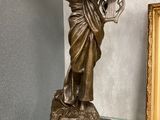 une statue représentant une femme tenant un panier, posée sur une table en verre