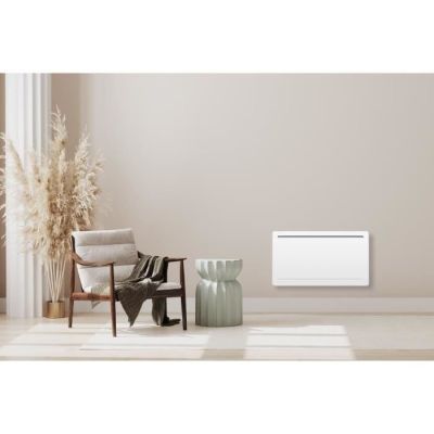 a white electric radiator sitting in a room next to a chair
