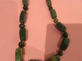 collier composé de perles de verre vertes, exposé dans un musée
