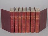 six red books are lined up in a row on a gray surface