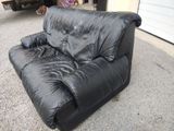 a black couch that is sitting in the middle of a driveway