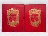 deux livres rouges ornés de dorures, posés sur une surface blanche