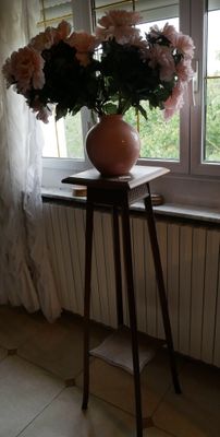 un vase de fleurs posé sur une table près d'une fenêtre