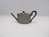 a close up of a teapot on a table with a spoon