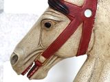 a wooden horse head with a red bridle on it ' s face