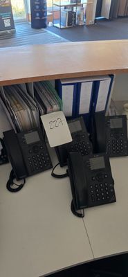 Plusieurs téléphones sont alignés sur un bureau dans un bureau.