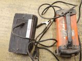 an orange and black device and a charger on the floor