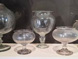 de nombreux verres et vases posés sur une étagère dans une pièce