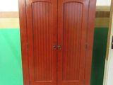 une armoire en bois à deux portes, avec un tiroir en dessous