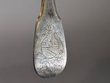 a silver spoon with a silver handle hanging from it ' s side