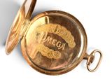 a gold pocket watch with the word omega written on it