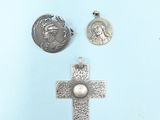 two silver crosses and a coin are on a blue surface