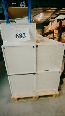 un réfrigérateur blanc posé sur une palette dans un entrepôt