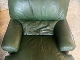 fauteuil inclinable en cuir vert dans une pièce avec un mur de briques en arrière-plan