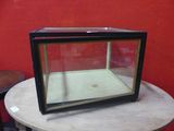 a glass display case sitting on a table in front of a red wall