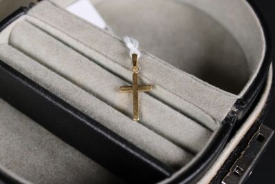 une petite croix en or dans un écrin posé sur une table