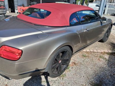 une voiture argentée au toit rouge garée devant un immeuble