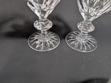 two wine glasses sitting on a table with a black background