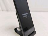 a black samsung phone on a stand on a white surface